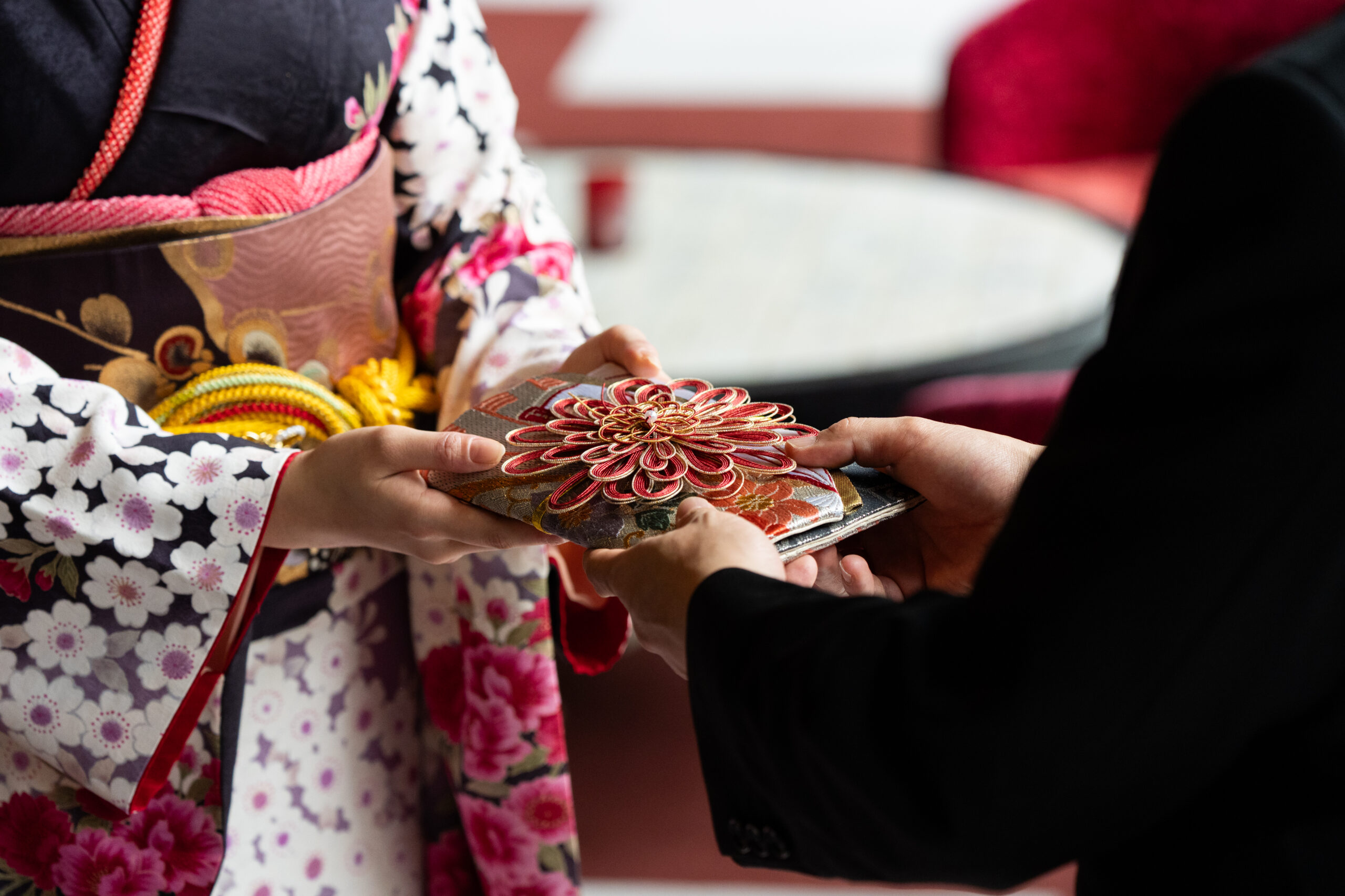 晴れ着をきた女性にご祝儀袋を渡す父親の手