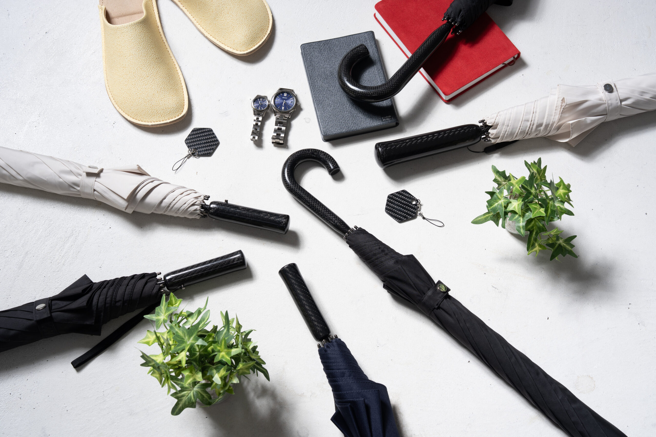 カーブ持ち手のCarbrella、専用傘カバー、カーボン製ネームタグを並べたスタイリング
